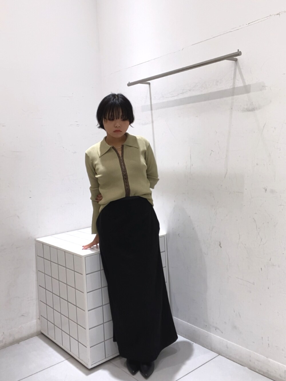 ブラック系のスカート、イエロー系のカーディガン/ボレロ、ブラック系のブーツを着用したレディースの秋コーディネートの3枚目の写真