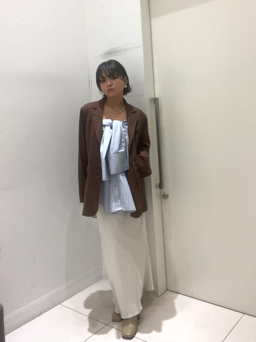 ブルー系のシャツ/ブラウス、ブラウン系のその他アウター、ホワイト系のスカートを着用したレディースの秋コーディネートの2枚目の写真