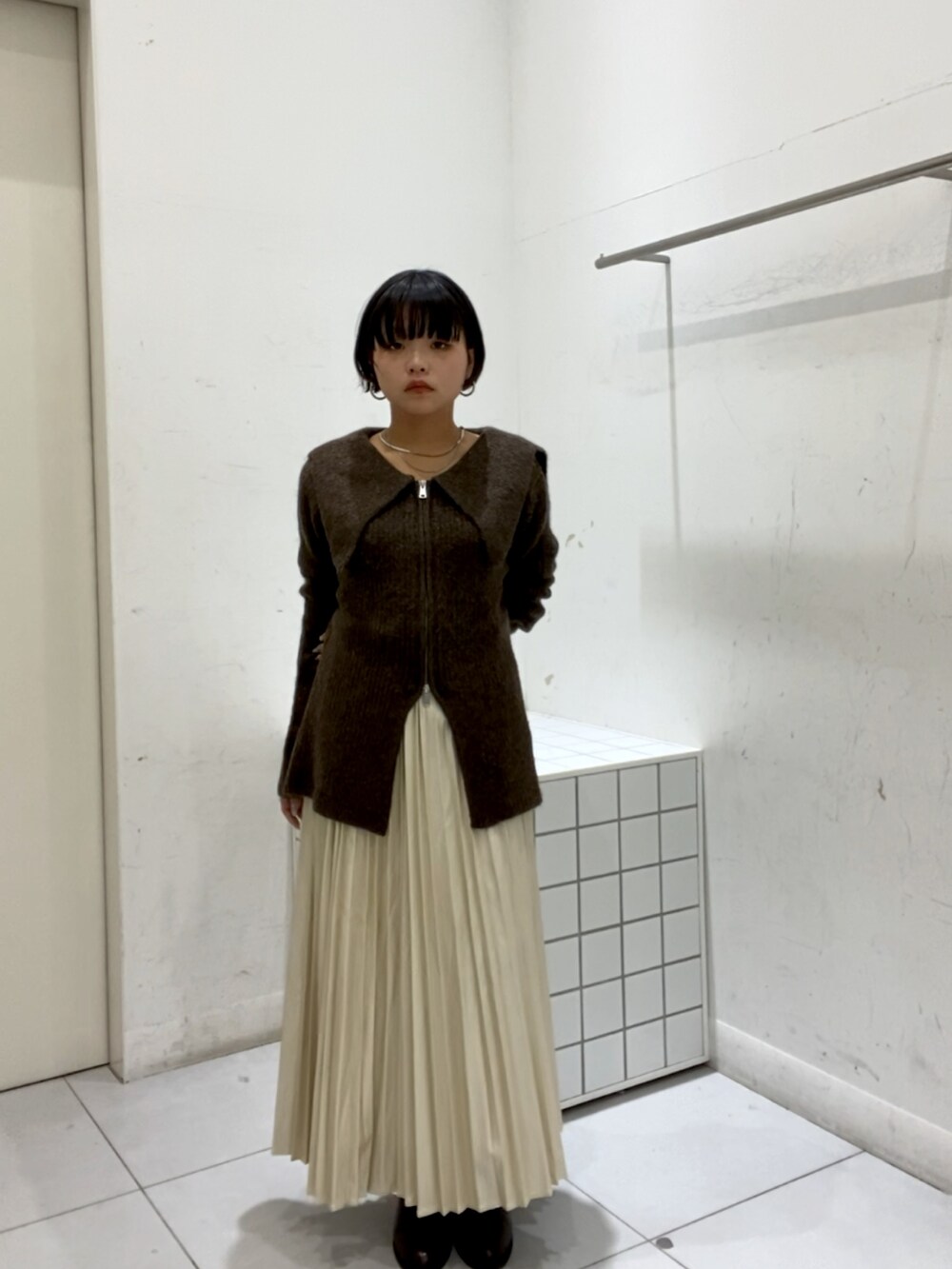 ブラウン系のカーディガン/ボレロ、ホワイト系のスカートを着用したレディースの秋コーディネートの2枚目の写真