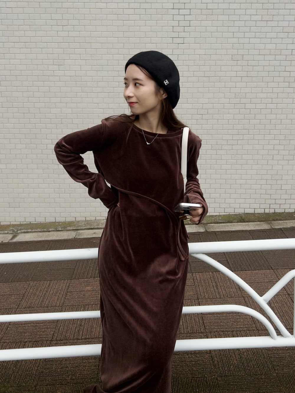 ホワイト系のバッグ、ブラウン系のワンピース、ブラック系のスニーカーを着用したレディースの冬コーディネートの7枚目の写真