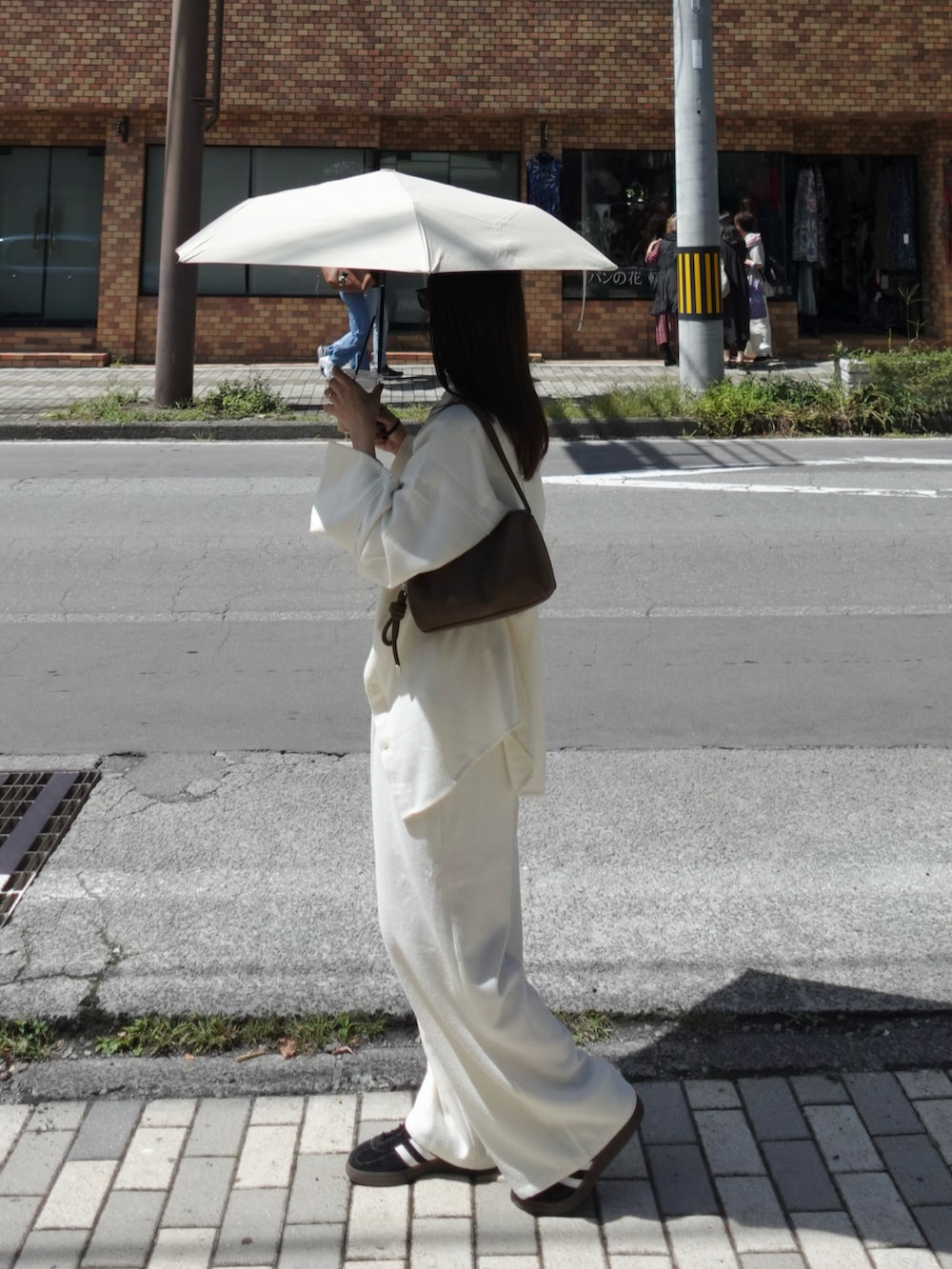 ホワイト系のシャツ/ブラウス、ホワイト系のその他パンツ、ブラウン系のショルダーバッグを着用したレディースの秋コーディネートの5枚目の写真