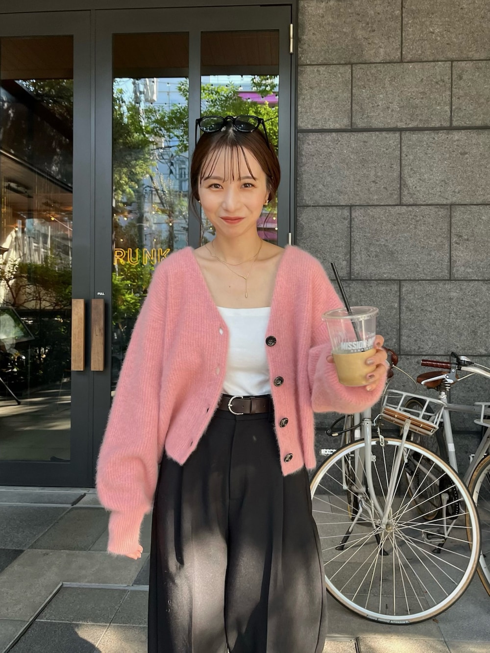 ブラック系のスラックス、ピンク系のカーディガン/ボレロ、ホワイト系のタンクトップを着用したレディースの夏コーディネートの3枚目の写真