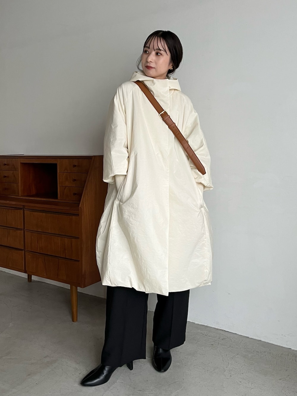 ブラック系のスラックス、ベージュ系のショルダーバッグ、ホワイト系のダウンジャケット/コートを着用したレディースの冬コーディネートの2枚目の写真