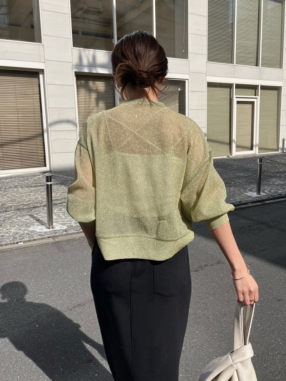 ブラック系のスカート、ホワイト系のハンドバッグ、ブラック系のブーツを着用したレディースの春コーディネートの5枚目の写真