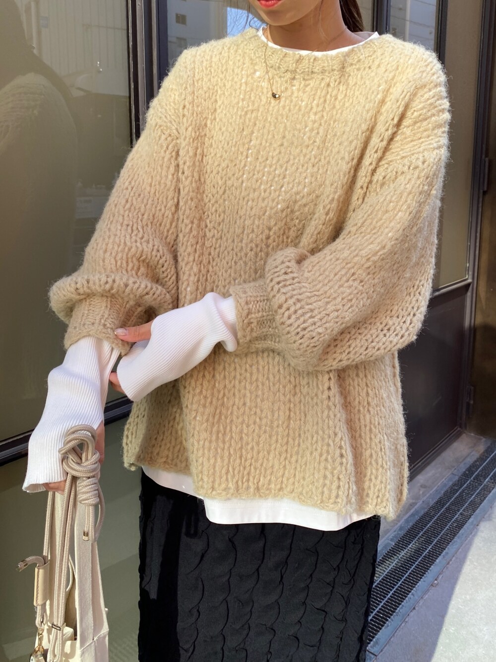 ブラック系のスカート、ベージュ系のニット/セーター、ホワイト系のTシャツ/カットソーを着用したレディースの秋コーディネートの5枚目の写真