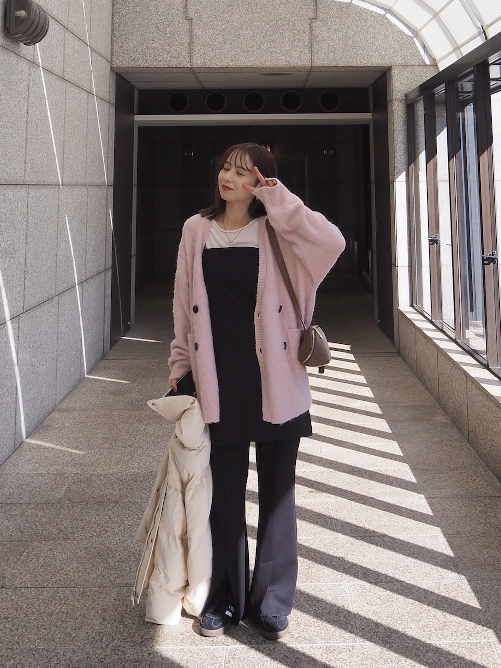 イエロー系のショルダーバッグ、ピンク系のカーディガン/ボレロ、ブラック系のスニーカーを着用したレディースの冬コーディネートの4枚目の写真