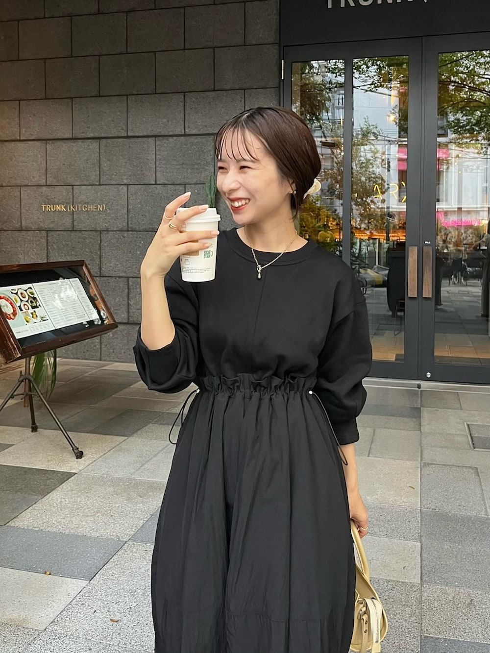 ブラック系のワンピース、ベージュ系のバッグ、ブラック系のブーツを着用したレディースの秋コーディネートの3枚目の写真