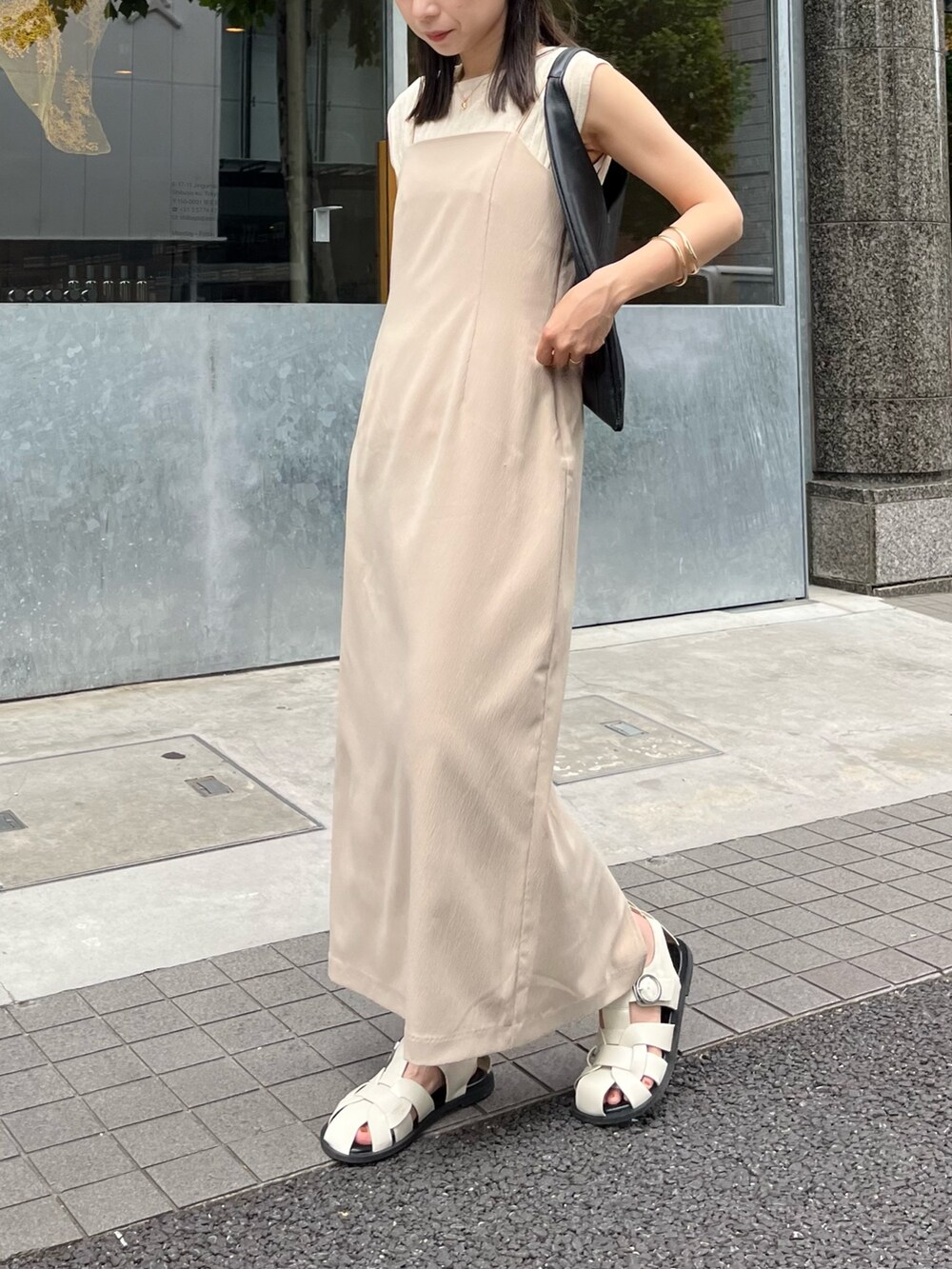 ベージュ系のワンピース、ブラック系のバッグ、ホワイト系のニット/セーターを着用したレディースの夏コーディネートの2枚目の写真