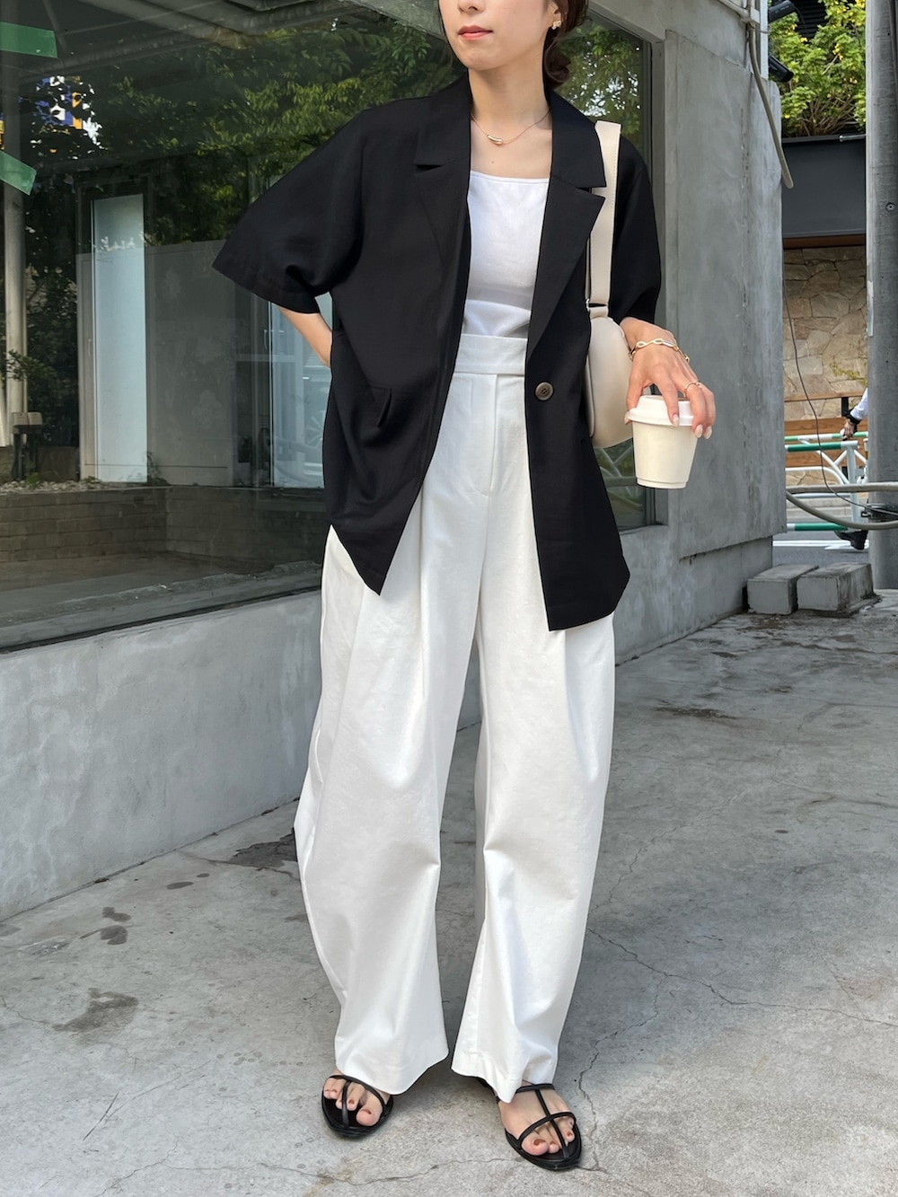 ブラック系のテーラードジャケット、ホワイト系のバッグ、ホワイト系のキャミソールを着用したレディースの春コーディネートの6枚目の写真