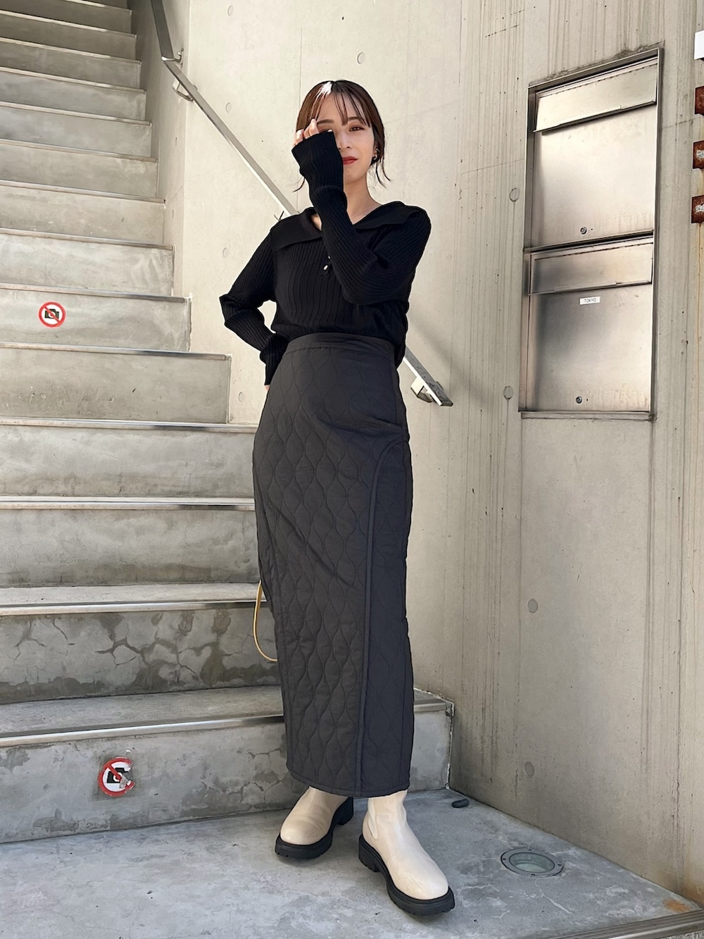 ブラック系のニット/セーター、ブラック系のスカート、イエロー系のハンドバッグを着用したレディースの秋コーディネートの2枚目の写真