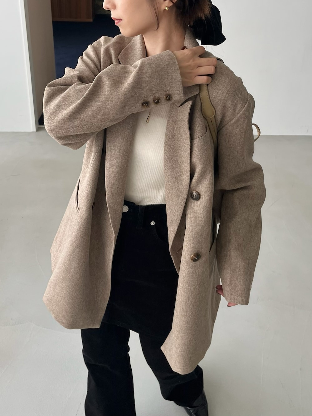 ホワイト系のニット/セーター、ベージュ系のテーラードジャケット、ブラック系のその他パンツを着用したレディースの秋コーディネートの4枚目の写真