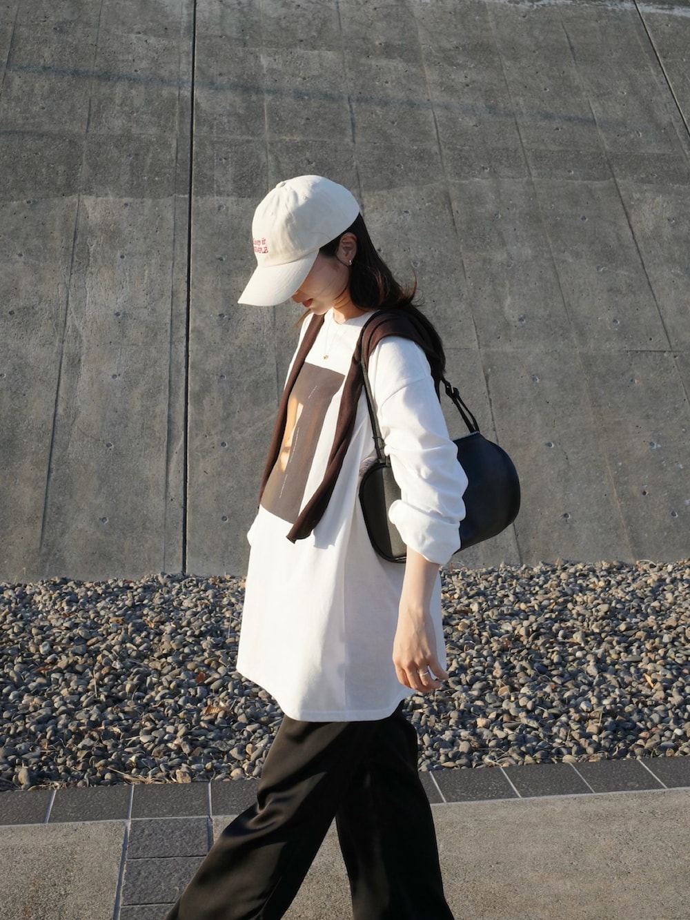 ブラック系のハンドバッグ、ブラック系のその他パンツ、ホワイト系のTシャツ/カットソーを着用したレディースの春コーディネートの4枚目の写真