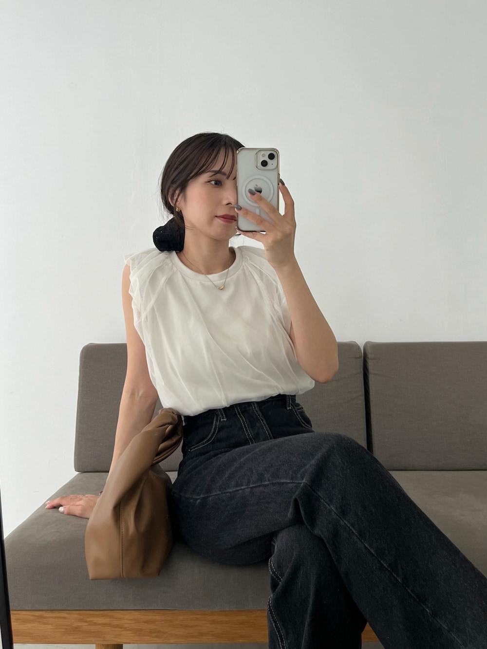 ブラック系のデニムパンツ、イエロー系のショルダーバッグ、ホワイト系のTシャツ/カットソーを着用したレディースの夏コーディネートの2枚目の写真