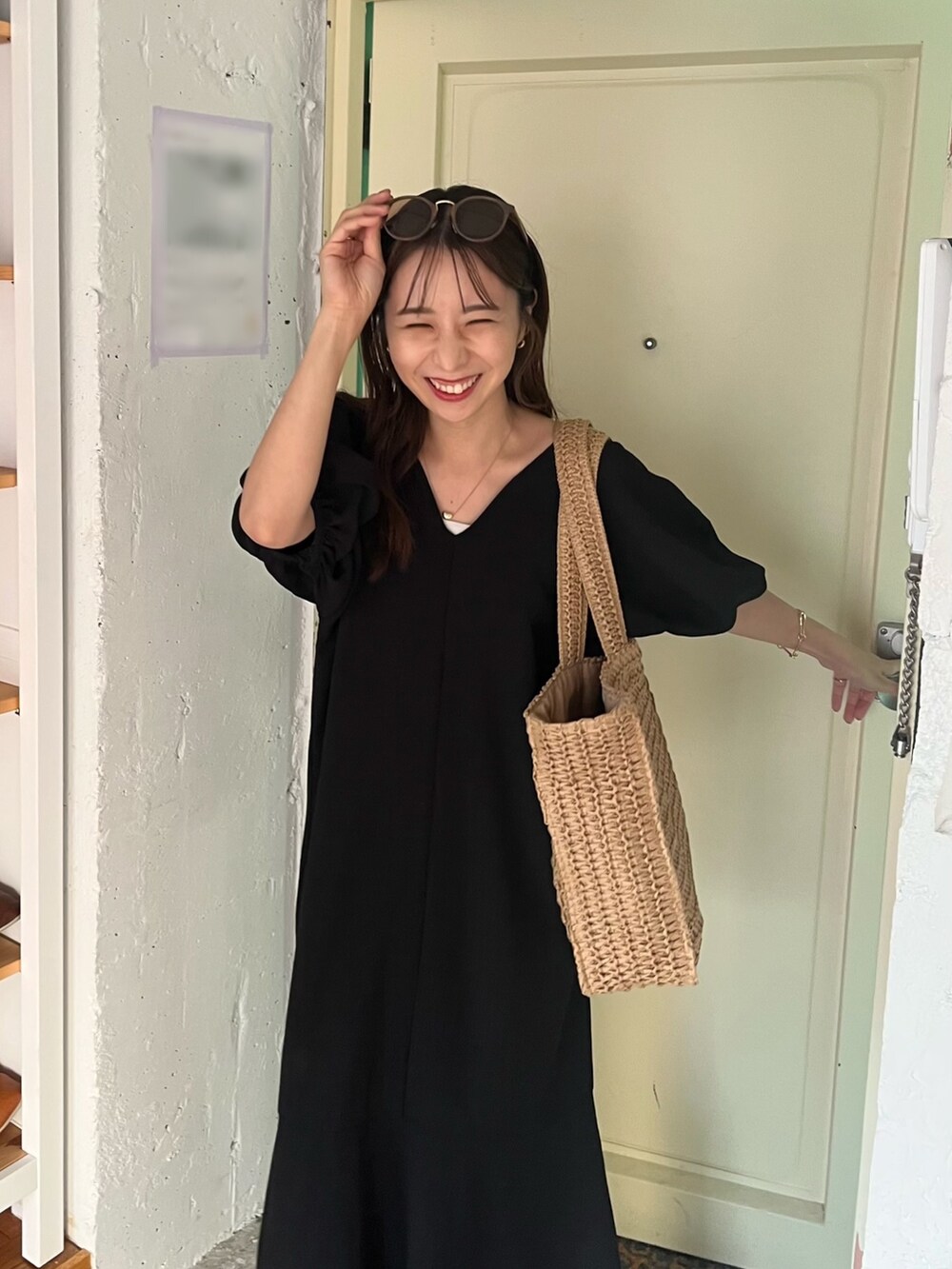 ブラック系のワンピース、ブラック系のサンダル、ベージュ系のバッグを着用したレディースの夏コーディネートの4枚目の写真