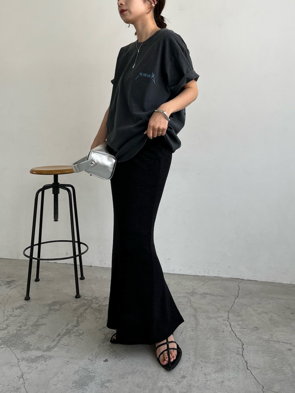 ブラック系のスカート、シルバー系のショルダーバッグ、ブラック系のサンダルを着用したレディースの夏コーディネートの2枚目の写真