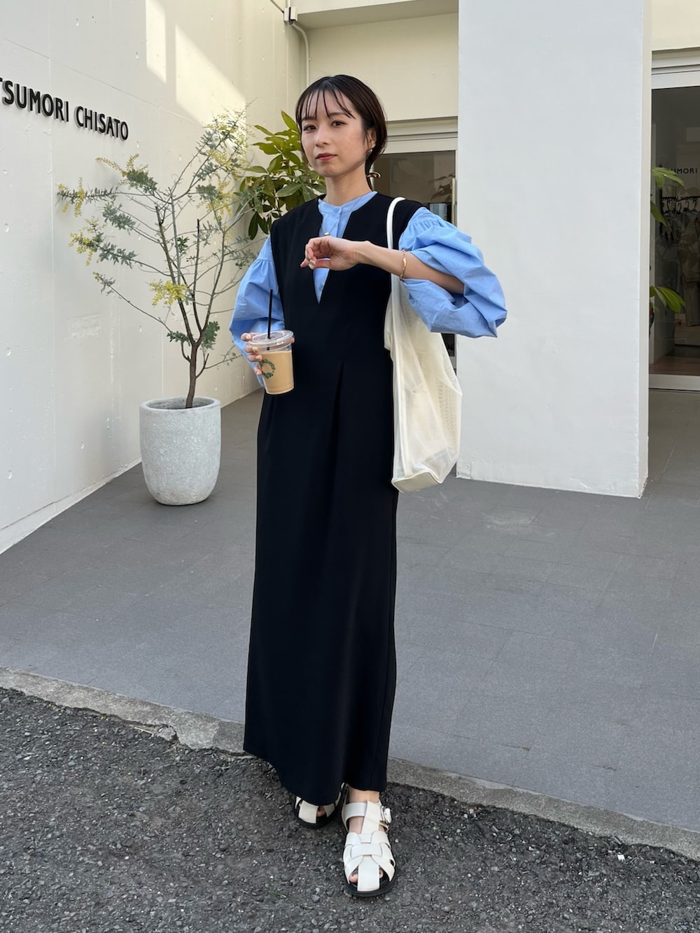 ブラック系のワンピース/ドレス、ブルー系のシャツ/ブラウス、ホワイト系のサンダルを着用したレディースの春コーディネートの2枚目の写真