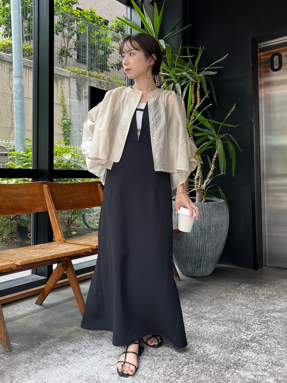 ベージュ系のシャツ/ブラウス、ブラック系のワンピース、ホワイト系のバッグを着用したレディースの夏コーディネートの2枚目の写真