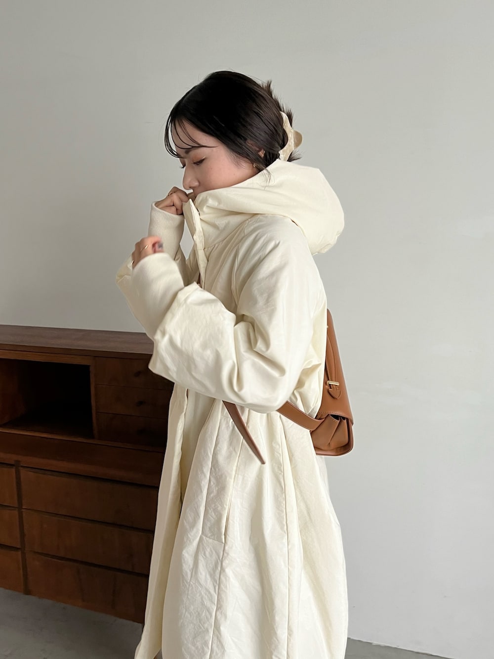 ブラック系のスラックス、ベージュ系のショルダーバッグ、ホワイト系のダウンジャケット/コートを着用したレディースの冬コーディネートの4枚目の写真