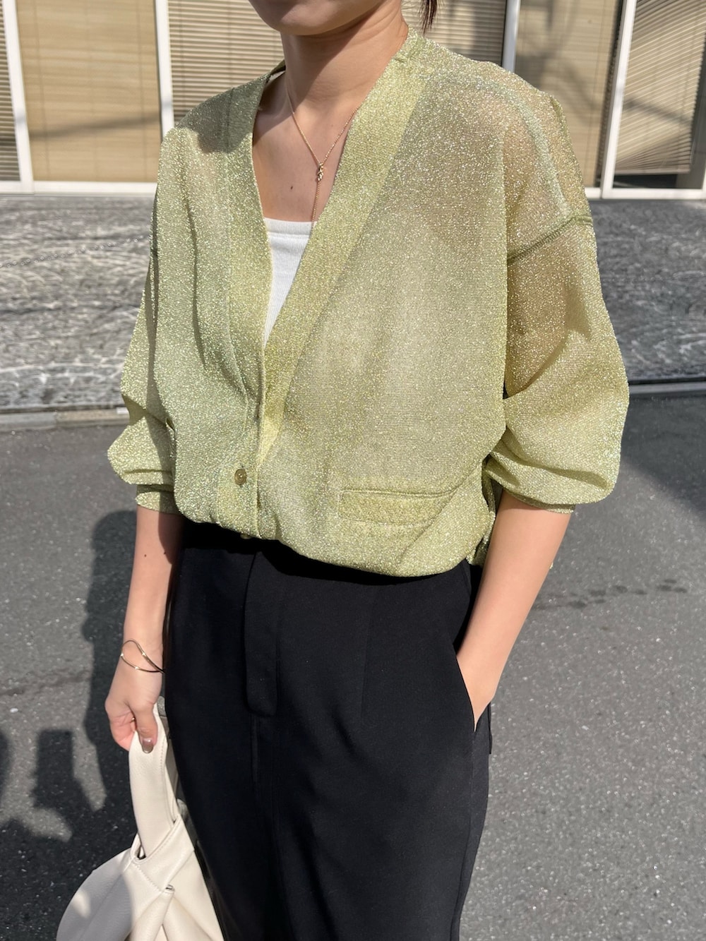 ブラック系のスカート、ホワイト系のハンドバッグ、ブラック系のブーツを着用したレディースの春コーディネートの4枚目の写真