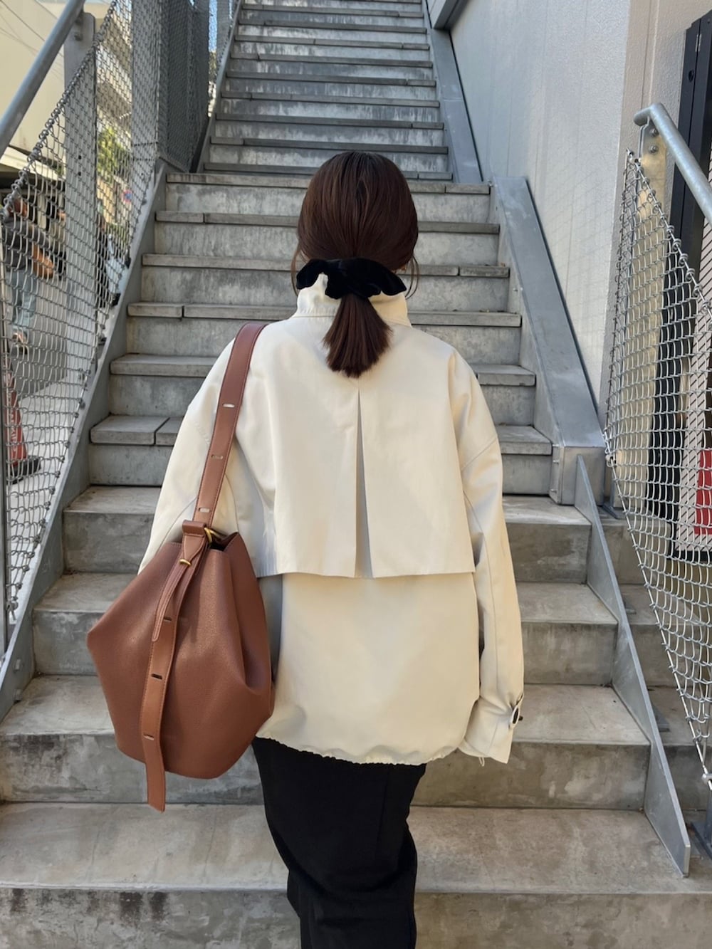 ホワイト系のその他アウター、ブラック系のスカート、イエロー系のショルダーバッグを着用したレディースの冬コーディネートの5枚目の写真