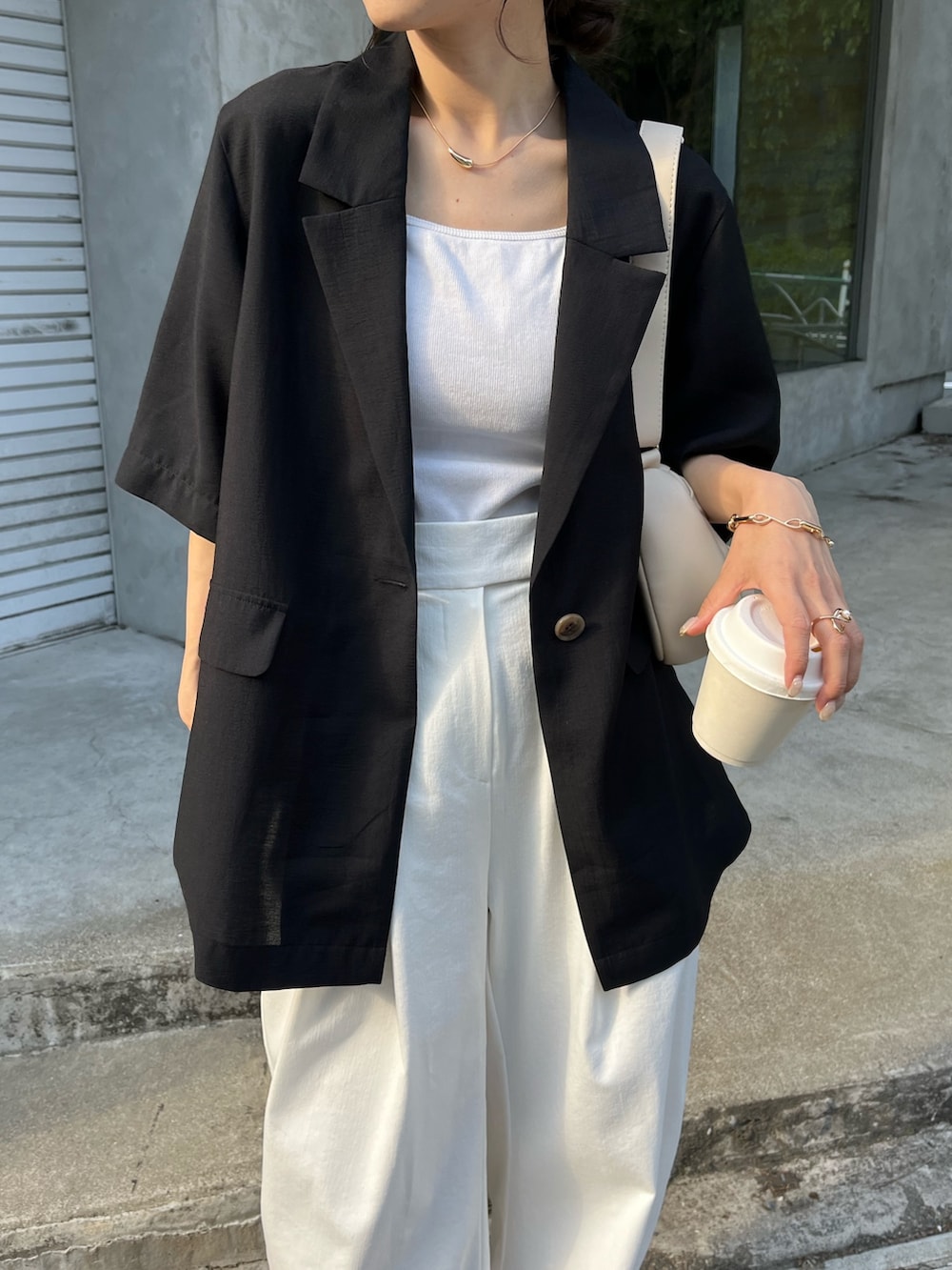 ブラック系のテーラードジャケット、ホワイト系のバッグ、ホワイト系のキャミソールを着用したレディースの春コーディネートの5枚目の写真