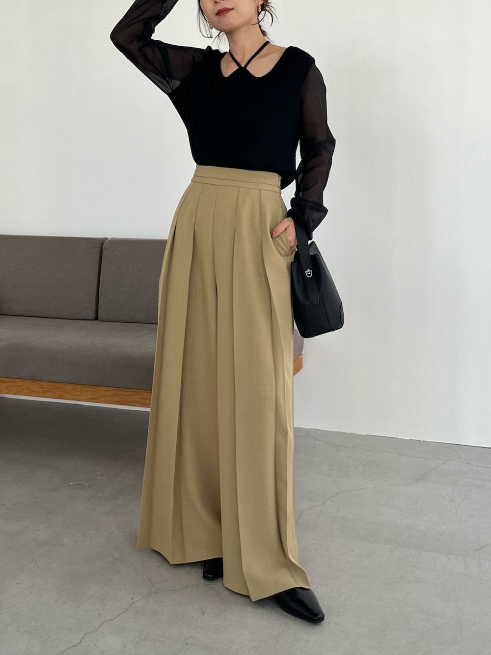 ベージュ系のその他パンツ、ブラック系のニット/セーター、ブラック系のショルダーバッグを着用したレディースの冬コーディネートの2枚目の写真