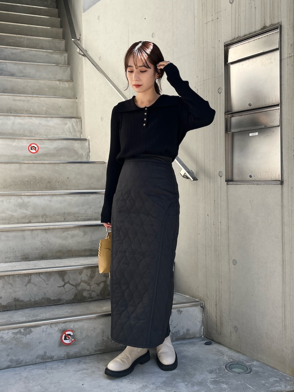 ブラック系のニット/セーター、ブラック系のスカート、イエロー系のハンドバッグを着用したレディースの秋コーディネートの3枚目の写真