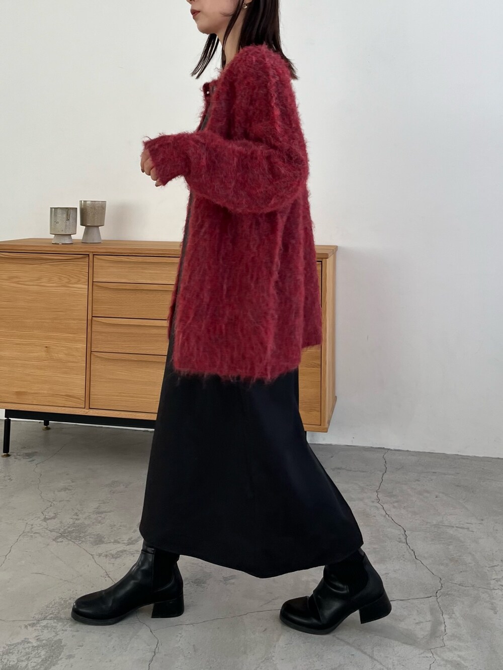 レッド系のカーディガン/ボレロ、ブラック系のワンピース、ホワイト系のハンドバッグを着用したレディースの冬コーディネートの3枚目の写真