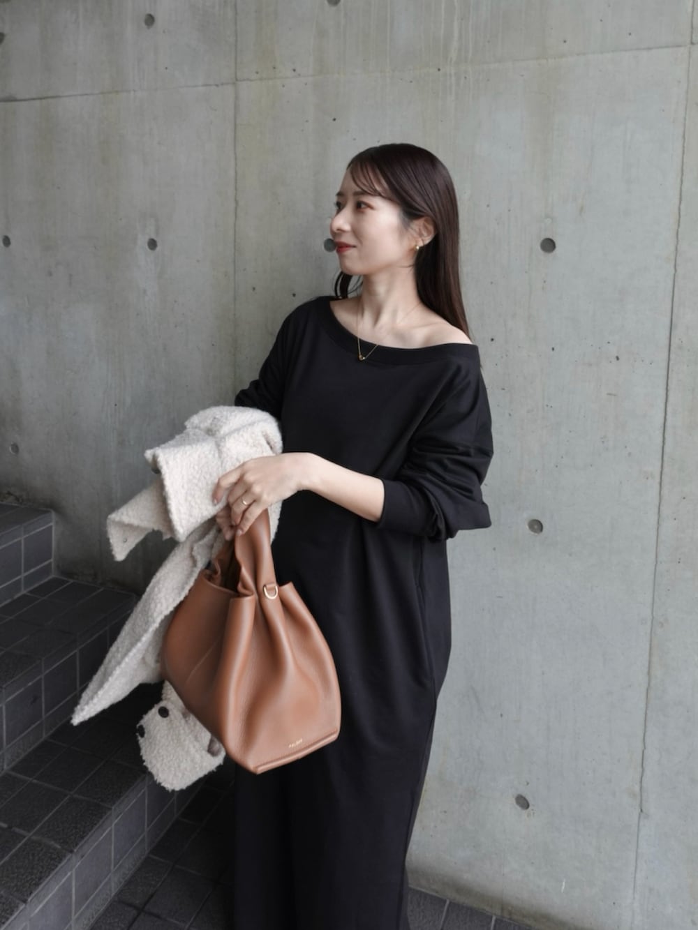 ブラック系のワンピース、ホワイト系のスニーカー、ブラウン系のバッグを着用したレディースの冬コーディネートの3枚目の写真