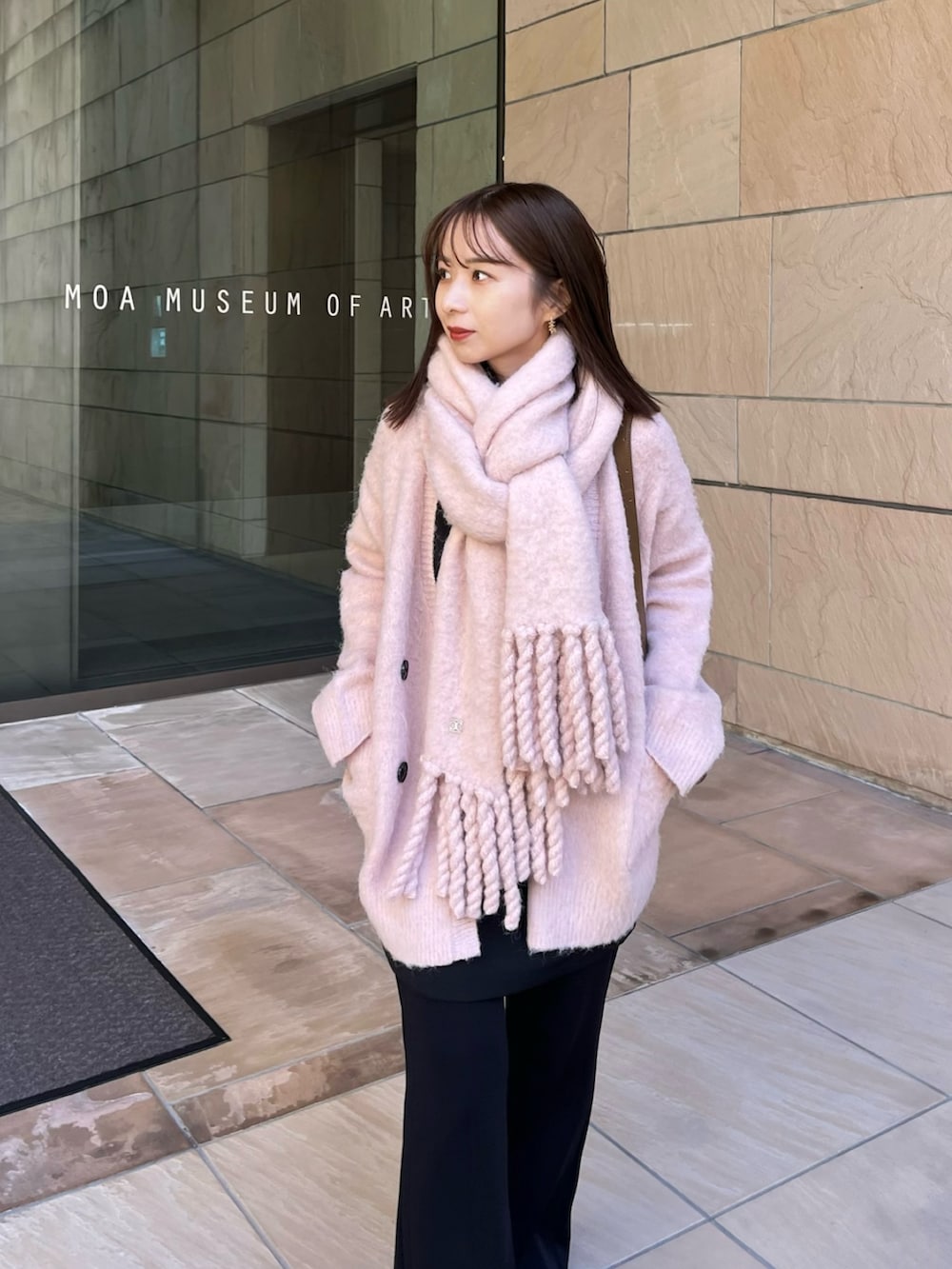 イエロー系のショルダーバッグ、ピンク系のカーディガン/ボレロ、ブラック系のスニーカーを着用したレディースの冬コーディネートの6枚目の写真