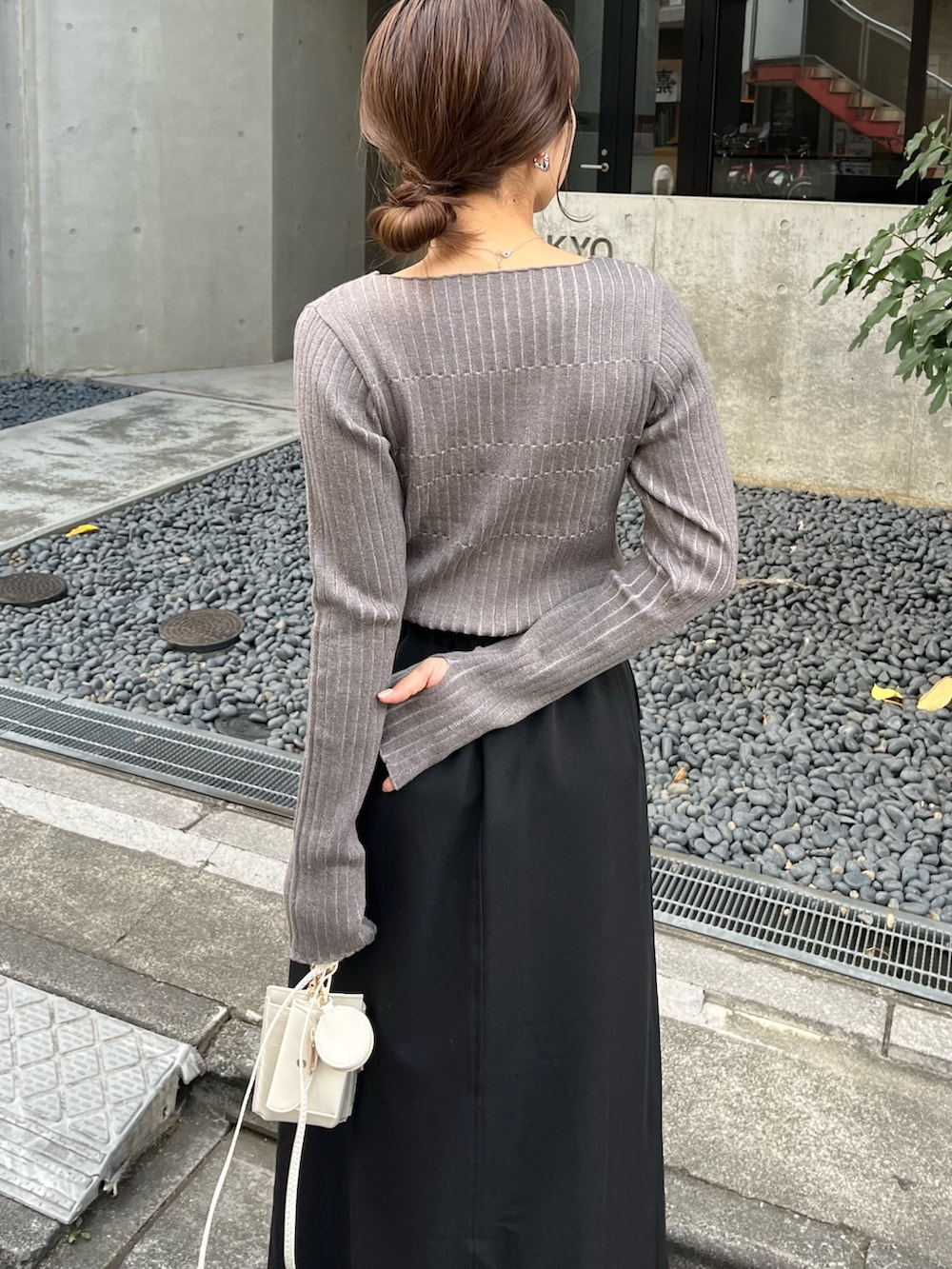 グレー系のニット/セーター、ブラック系のスカート、ブラック系のトートバッグを着用したレディースの秋コーディネートの4枚目の写真