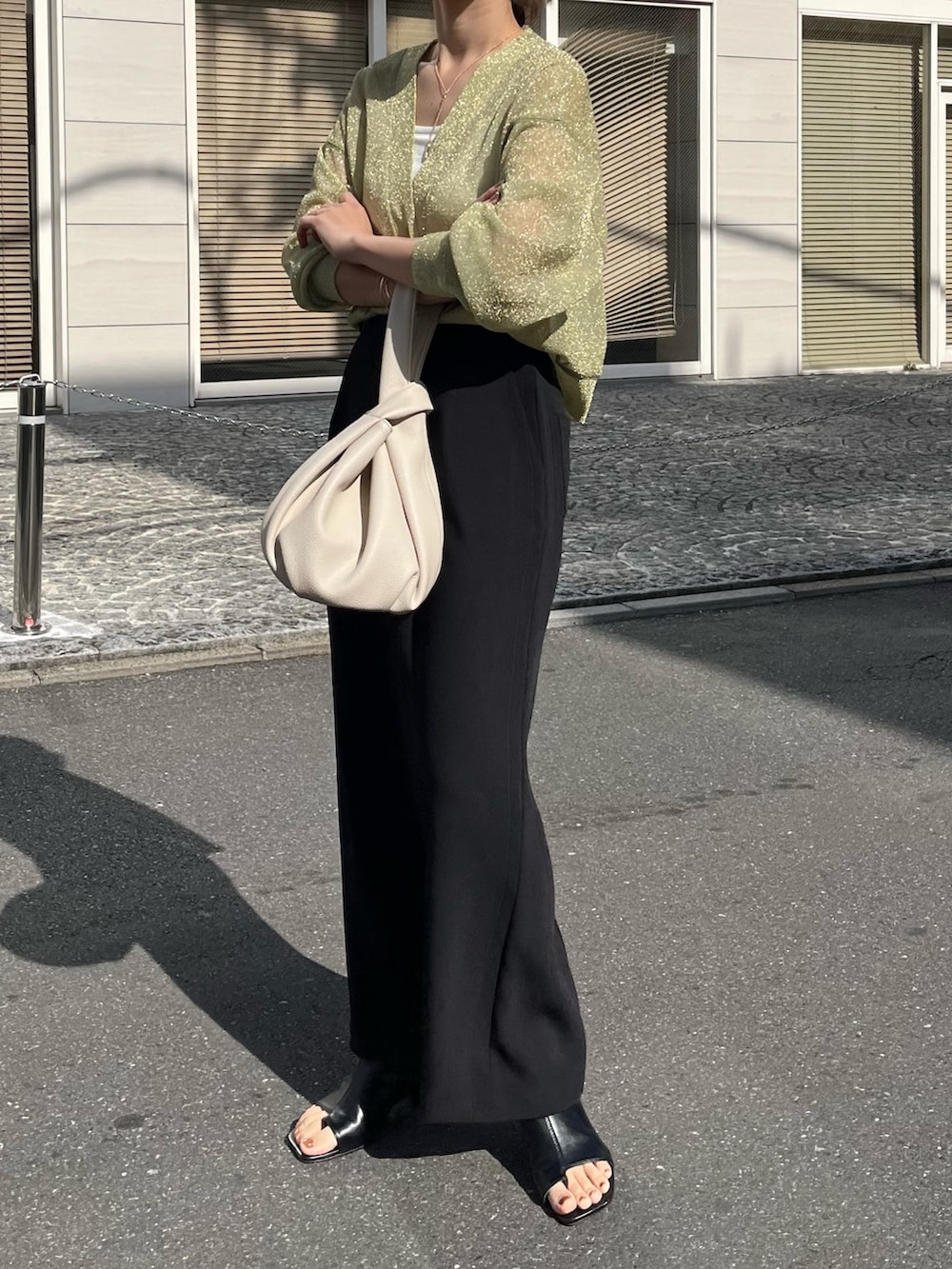 ブラック系のスカート、ホワイト系のハンドバッグ、ブラック系のブーツを着用したレディースの春コーディネートの2枚目の写真