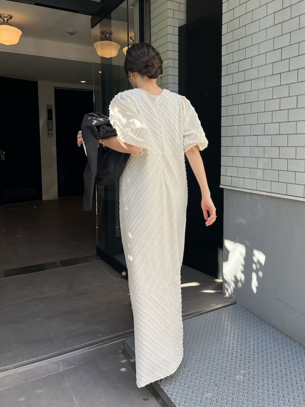 ホワイト系のワンピース、ブラック系のショルダーバッグ、ブラック系のその他シューズを着用したレディースの春コーディネートの3枚目の写真