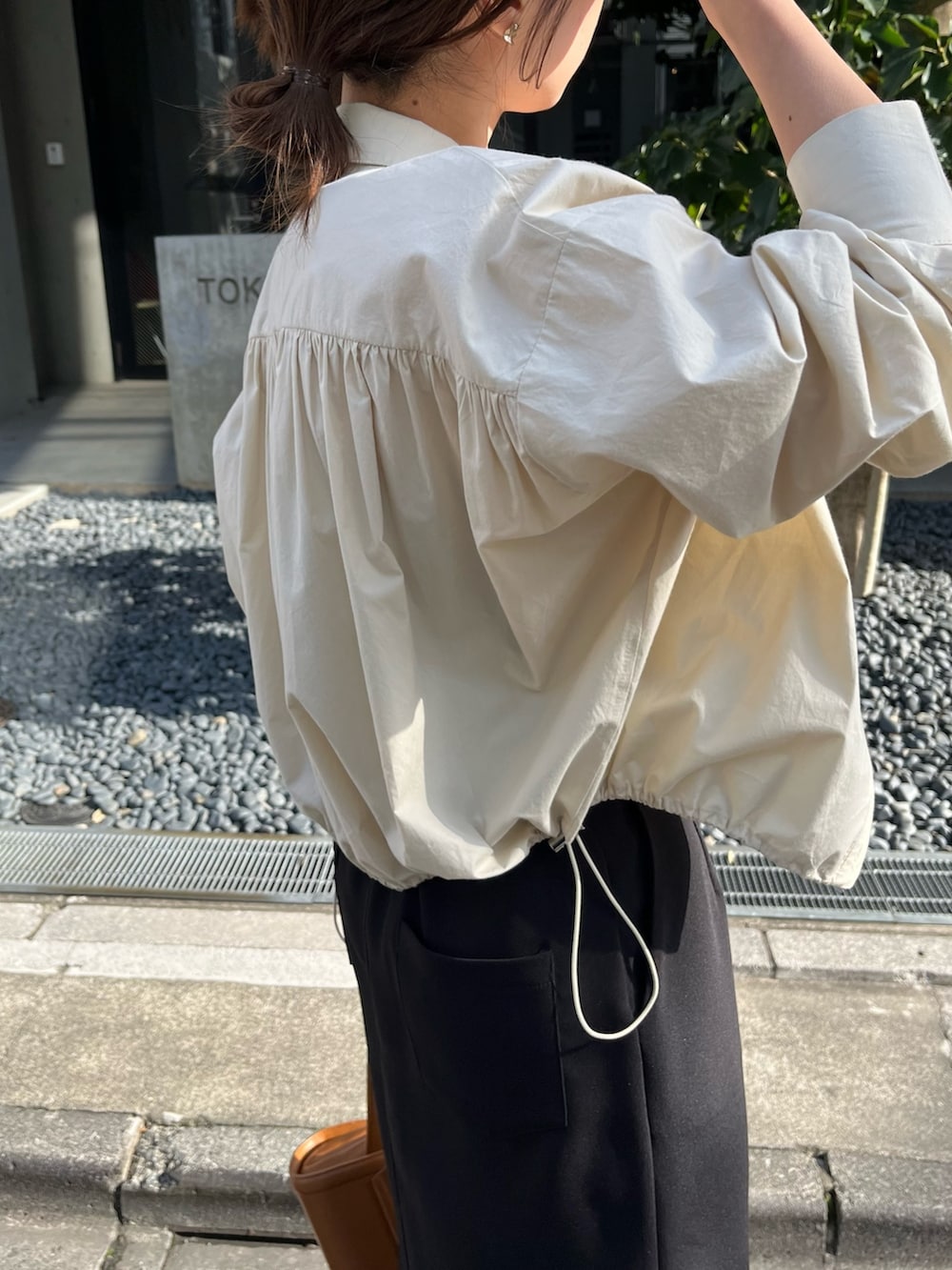 ブラック系のスカート、ベージュ系のショルダーバッグ、ブラック系のブーツを着用したレディースの春コーディネートの5枚目の写真