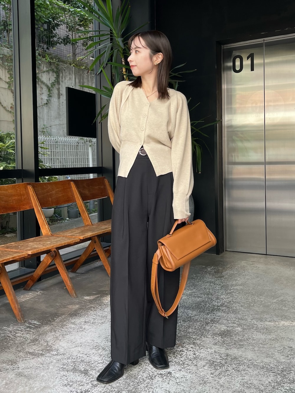 ブラック系のスラックス、ベージュ系のショルダーバッグ、ベージュ系のカーディガン/ボレロを着用したレディースの冬コーディネートの2枚目の写真