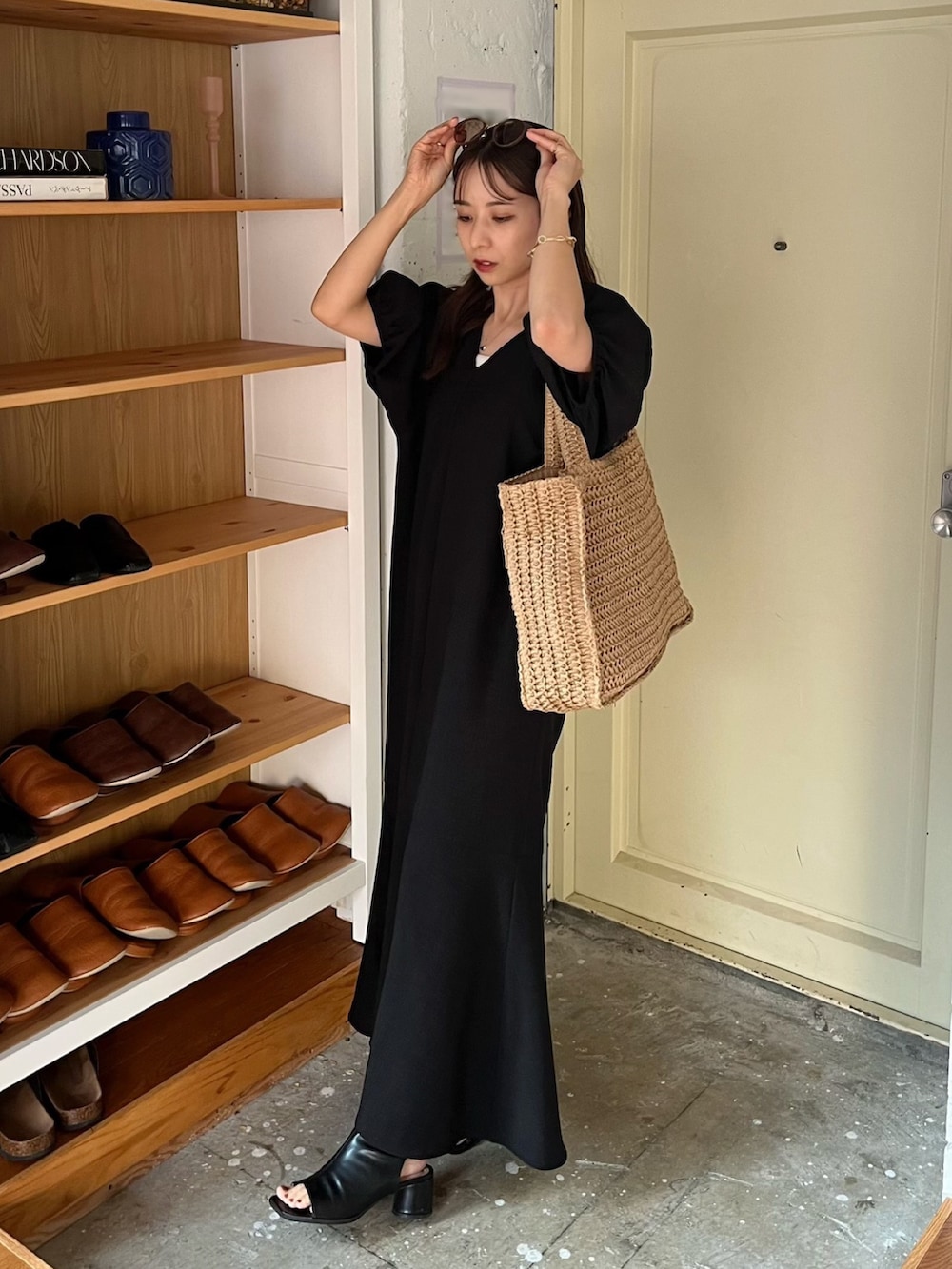 ブラック系のワンピース、ブラック系のサンダル、ベージュ系のバッグを着用したレディースの夏コーディネートの2枚目の写真