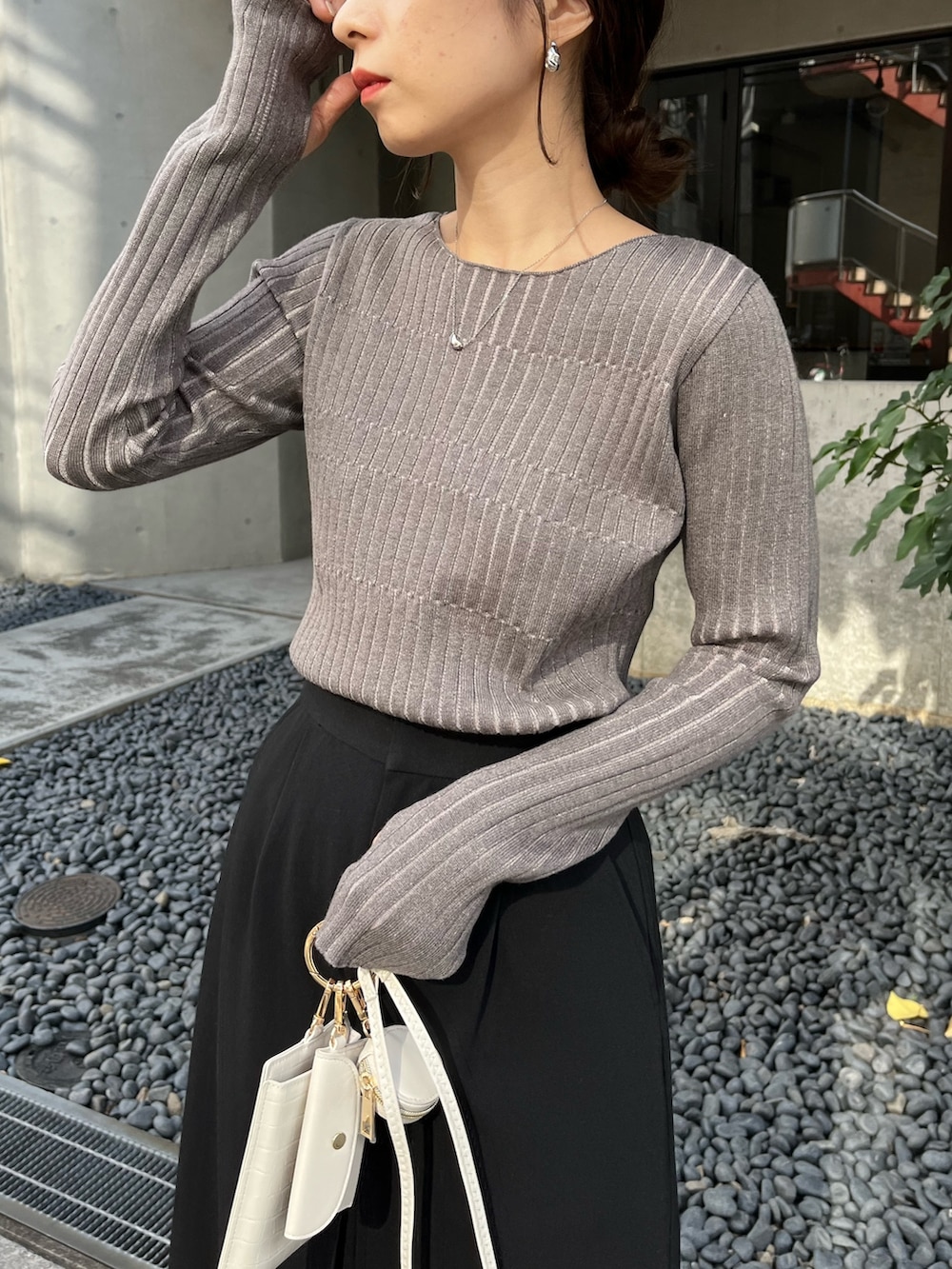 グレー系のニット/セーター、ブラック系のスカート、ブラック系のトートバッグを着用したレディースの秋コーディネートの2枚目の写真