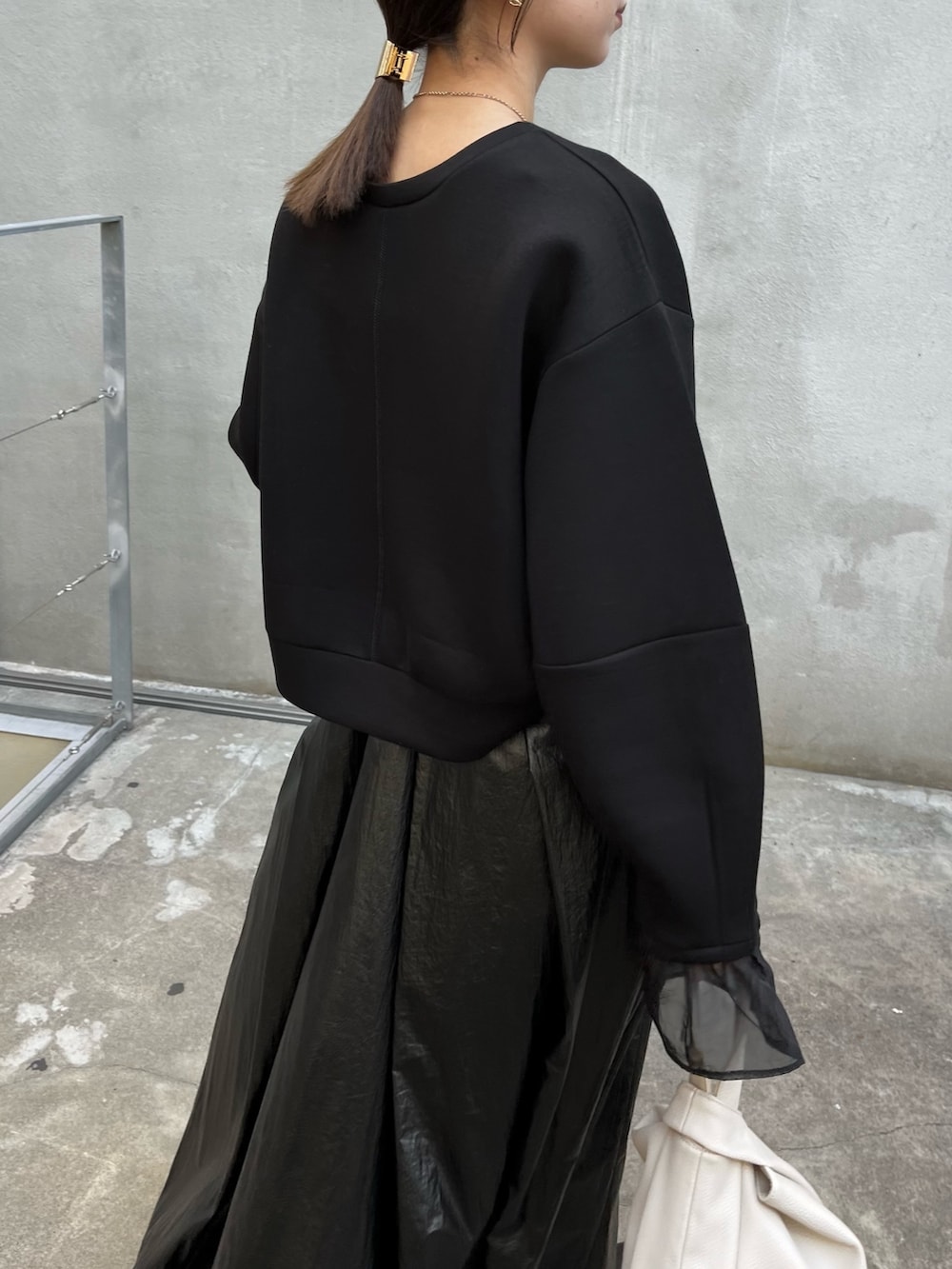 ブラック系のスカート、ブラック系のスウェット、ホワイト系のハンドバッグを着用したレディースの冬コーディネートの6枚目の写真