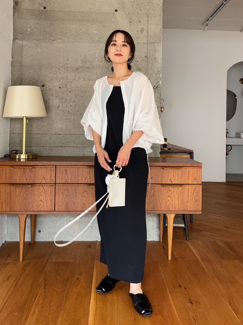 ブラック系のワンピース、ホワイト系のブルゾン、ブラック系のトートバッグを着用したレディースの夏コーディネートの2枚目の写真