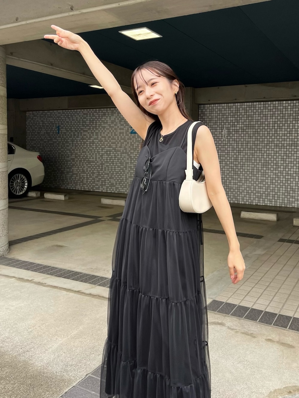 ブラック系のワンピース、ブラック系のその他シューズ、ホワイト系のショルダーバッグを着用したレディースの夏コーディネートの4枚目の写真