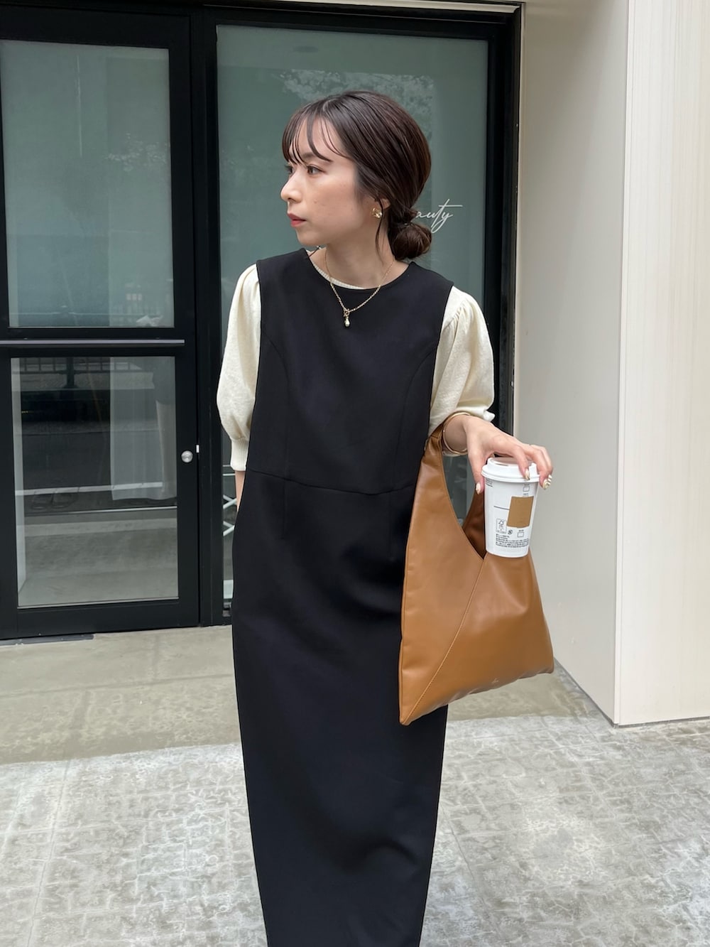 ブラック系のジャンパースカート、ホワイト系のニット/セーター、イエロー系のバッグを着用したレディースの春コーディネートの3枚目の写真