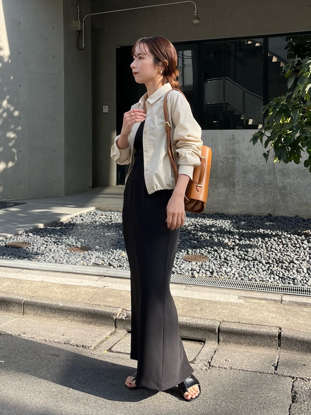 ブラック系のスカート、ベージュ系のショルダーバッグ、ブラック系のブーツを着用したレディースの春コーディネートの2枚目の写真