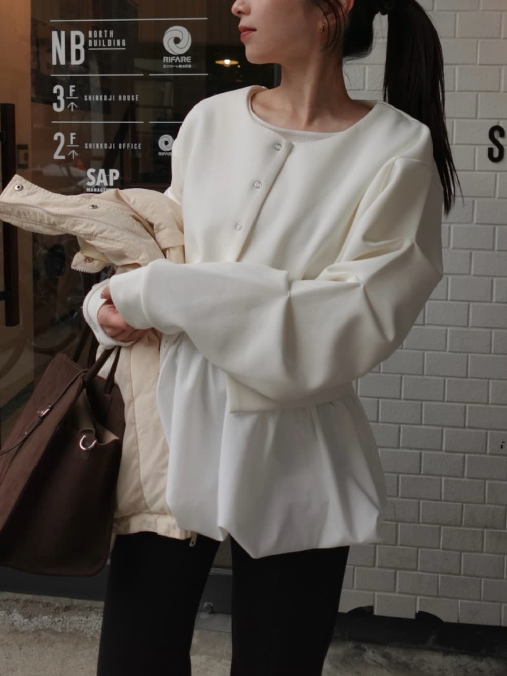 ホワイト系のTシャツ/カットソー、ホワイト系のTシャツ/カットソー、ブラウン系のバッグを着用したレディースの冬コーディネートの3枚目の写真
