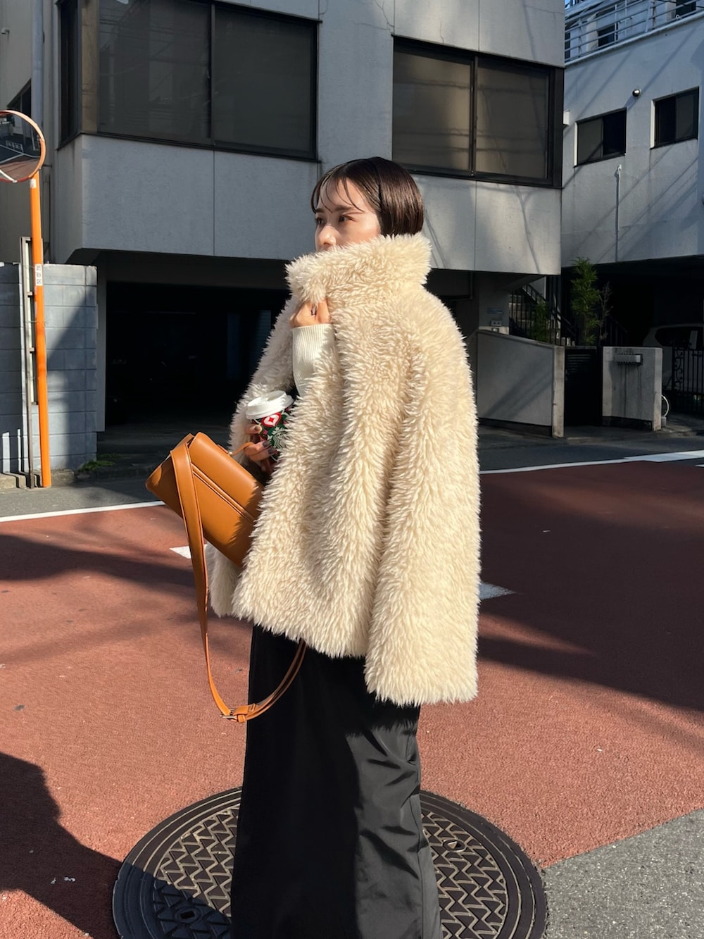 ブラック系のスカート、ホワイト系のニット/セーター、ホワイト系のダウンジャケット/コートを着用したレディースの冬コーディネートの6枚目の写真