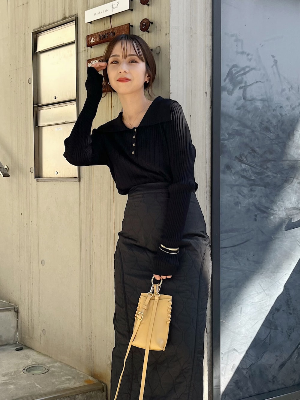 ブラック系のニット/セーター、ブラック系のスカート、イエロー系のハンドバッグを着用したレディースの秋コーディネートの4枚目の写真