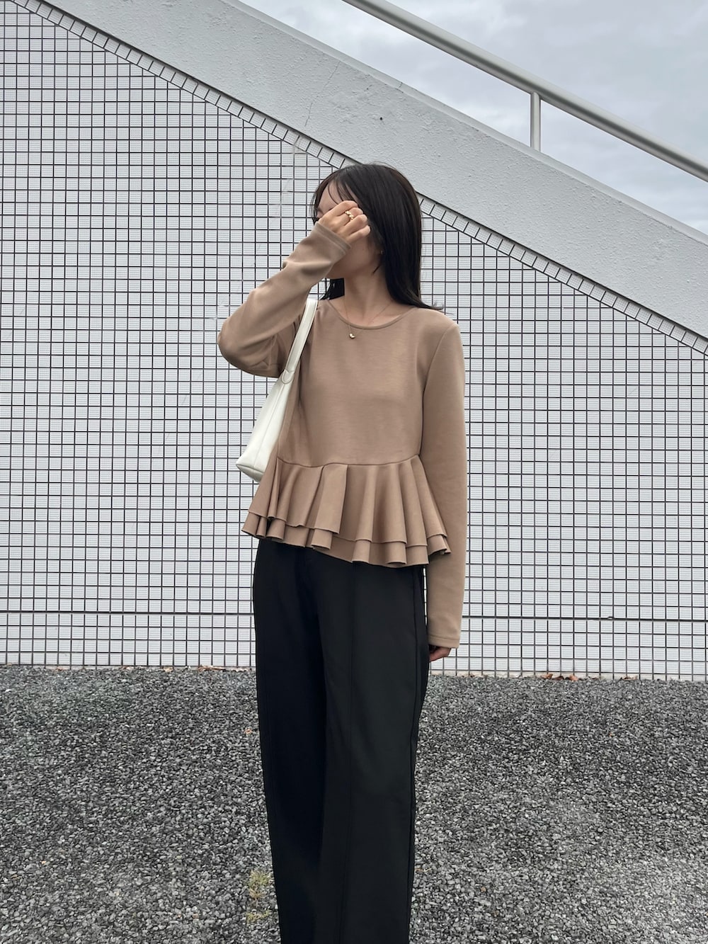 ベージュ系のTシャツ/カットソー、ブラック系のスラックス、ブラック系のローファーを着用したレディースの冬コーディネートの2枚目の写真