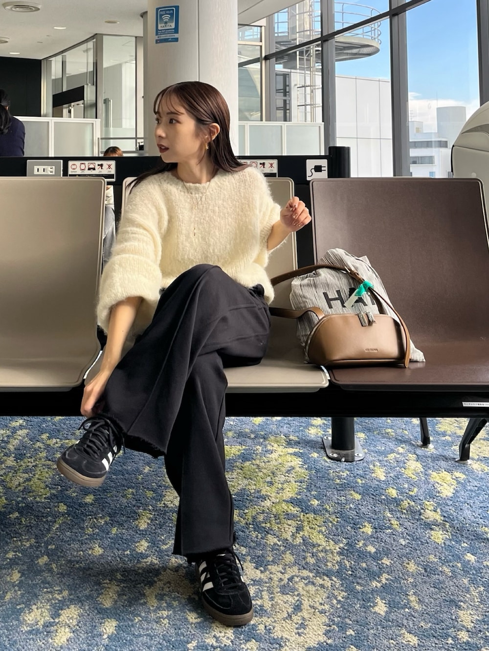 ブラック系のスウェットパンツ、ホワイト系のニット/セーター、ブラック系のスニーカーを着用したレディースの秋コーディネートの7枚目の写真