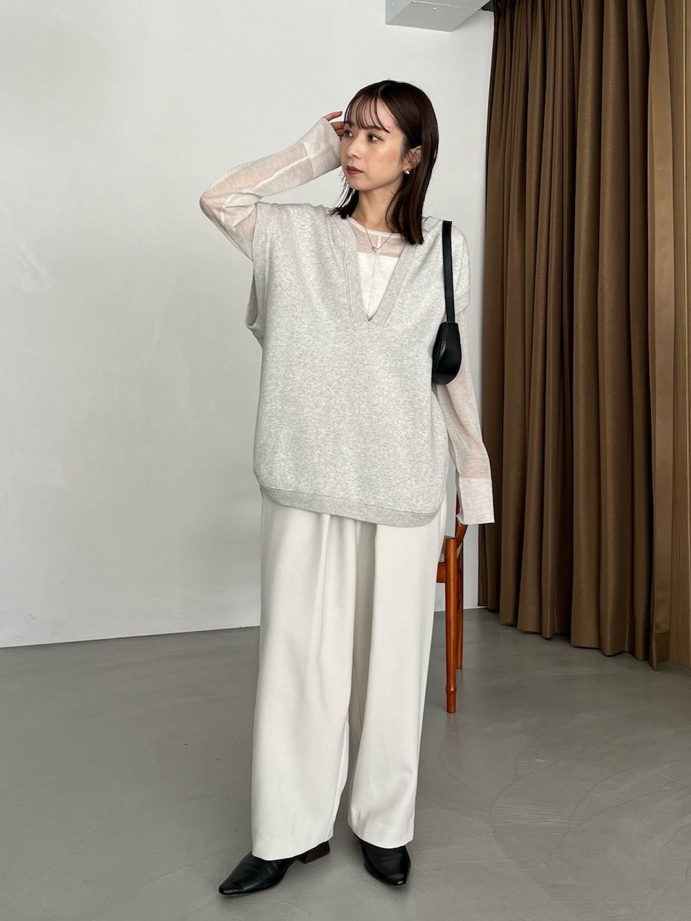 グレー系のベスト、ホワイト系のニット/セーター、ブラック系のパンプスを着用したレディースの秋コーディネートの2枚目の写真