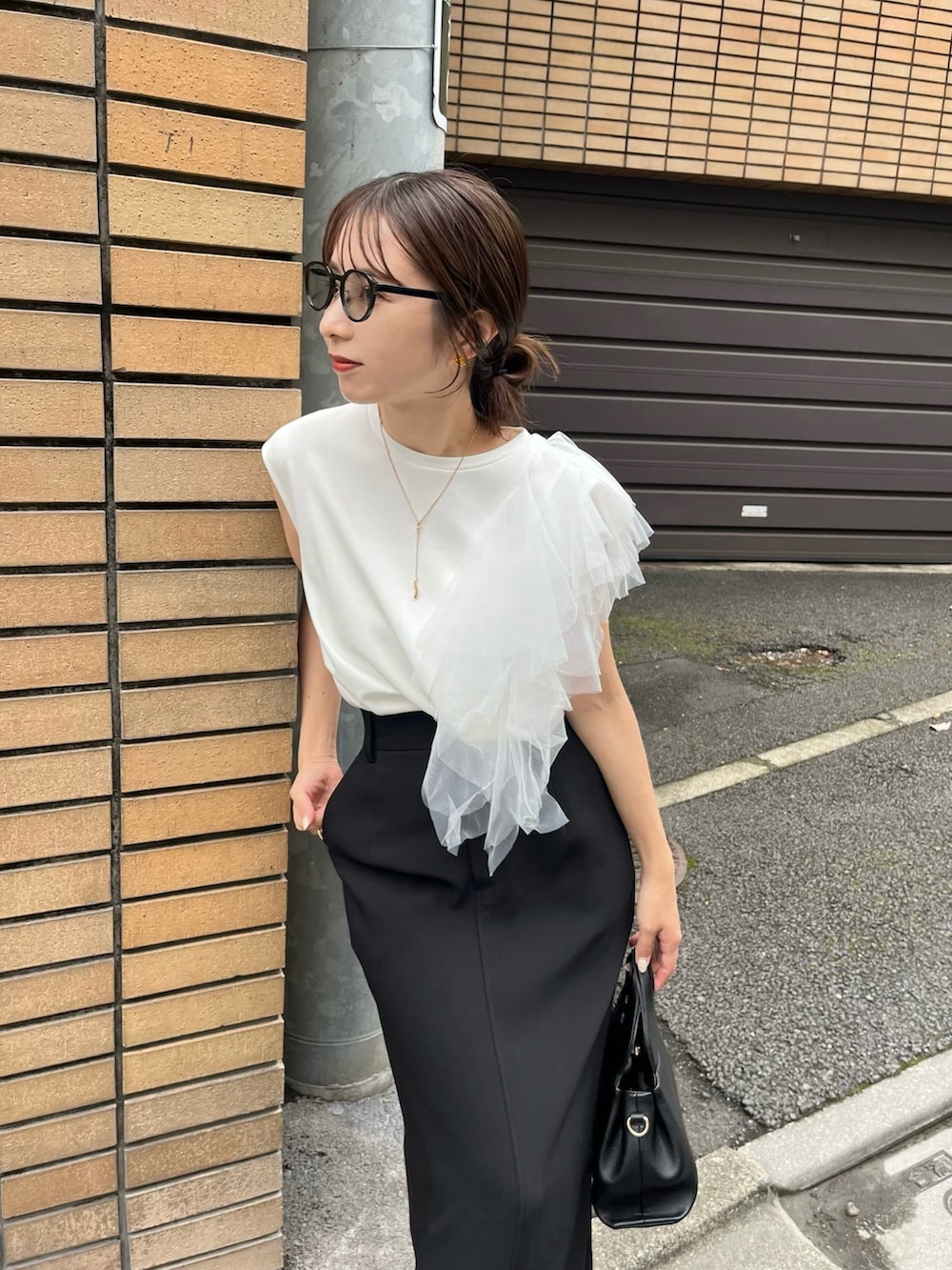 ブラック系のスカート、ホワイト系のTシャツ/カットソー、ブラック系のショルダーバッグを着用したレディースの夏コーディネートの4枚目の写真