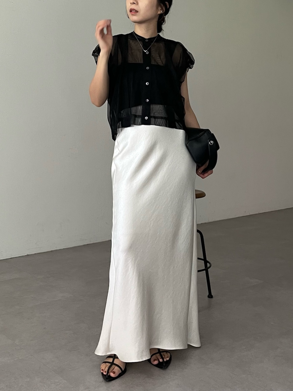 ホワイト系のスカート、ブラック系のシャツ/ブラウス、ブラック系のショルダーバッグを着用したレディースの夏コーディネートの2枚目の写真